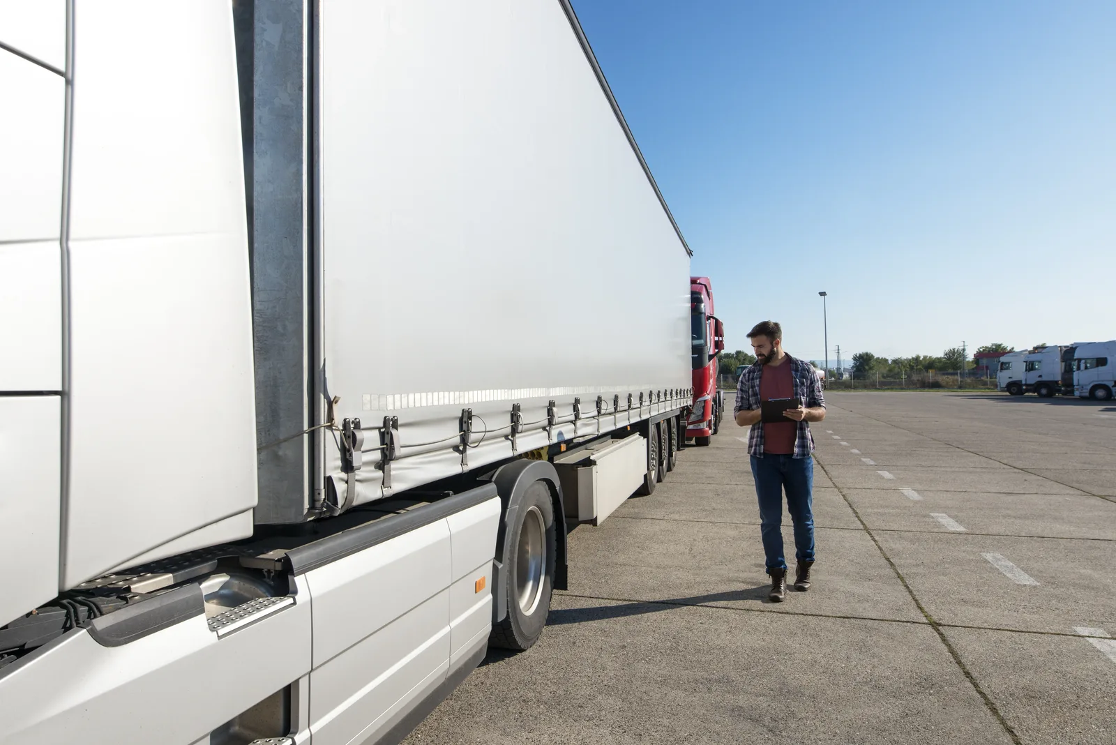 Mitarbeiter kontrolliert einen Lkw auf einem Betriebshof